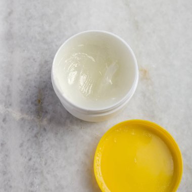 Yukarıdan mermer masada kozmetik krem ile kase