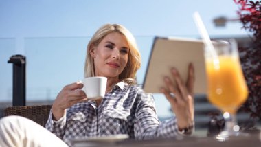 Kahve içme ve kafede tablet bilgisayar kullanarak genç iş kadını