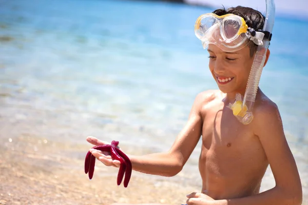 男孩持有红色五点海星和网在他的手在海滩上 — 图库照片