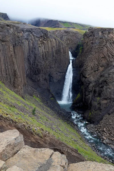 Breathtaking Litlanesfoss waterfall at east of Iceland. Waterfall is framed by basalt columns. Summer Iceland hike.