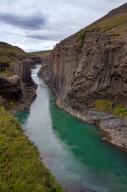 İzlanda 'daki Jokuldalur Vadisi' ndeki Studlagil Kanyonu 'nun nefes kesici manzarası. Bazalt sütunlar ve turkuaz buzul nehri. En iyi seyahat yeri. Yaz yürüyüşü.