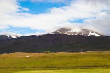Dağlardaki grafiksel kar yamaları. Yaz mevsimi kuzey manzarası. Doğu İzlanda. Yeşil çimenler ve yüksek topraklarda bir kar.