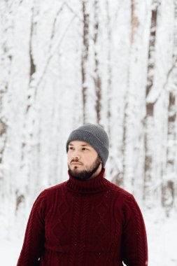 adam kırmızı örgü kazak ve kış ormanın içinde kar üzerinde duran bir telefon tutarak kot