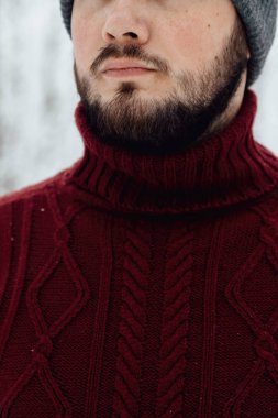 adam kırmızı örgü kazak ve kış ormanın içinde kar üzerinde duran bir telefon tutarak kot