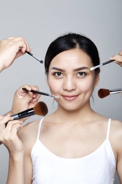 Güzellik Asyalı kadın portre kozmetik makyaj fırçaları yüz, kız moda Model yakınındaki ile. Mükemmel cilt. Shot kamera stüdyoda arıyorsunuz