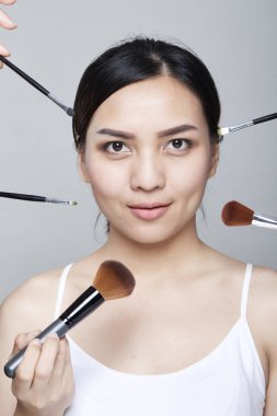 Güzellik Asyalı kadın portre kozmetik makyaj fırçaları yüz, kız moda Model yakınındaki ile. Mükemmel cilt. Shot kamera stüdyoda arıyorsunuz