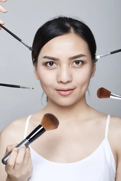 Beauty asian woman portrait cosmetics with make-up brushes near face,  Fashion Model Girl. Perfect Skin. Looking at camera studio shot