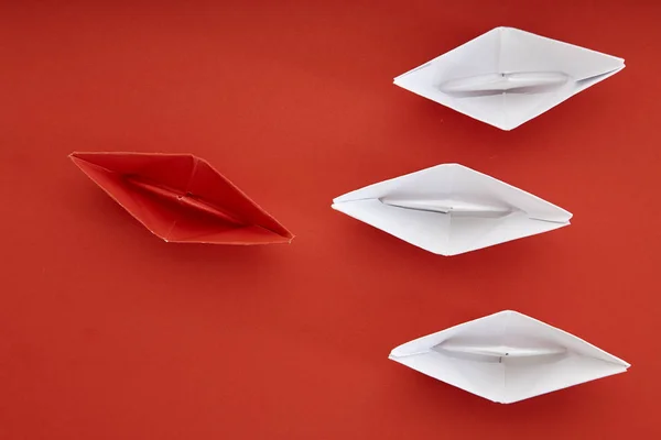 Leadership concept with red paper ship leading among white on red background with copy space. Business leadership concept. Minimal design