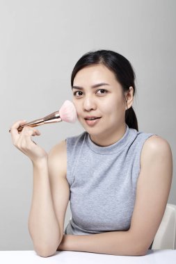 Püskül, cilt bakım kavramı ile yüzünde kozmetik toz uygulama güzel ve genç birbayan. Beyaz arka plan üzerinde fotoğraf