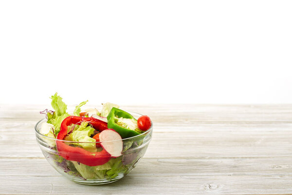 Full bowl of fresh salad on a white wooden table the background. Concept helpful and simple food