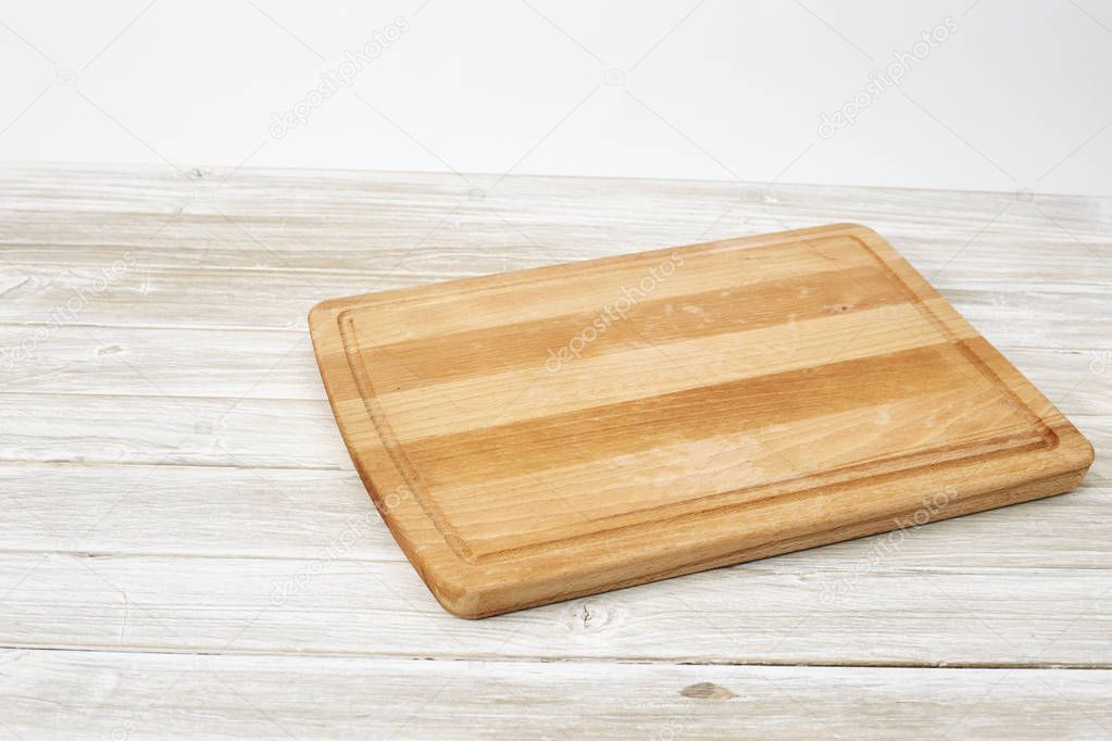 Empty bamboo cutting board on a white wooden table for product display.Top view