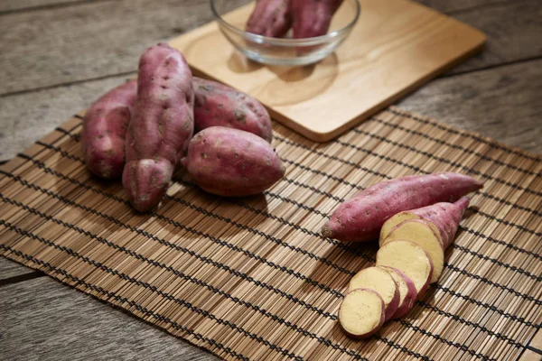 Raw purple sweet potato on rustic wooden table in kitchen