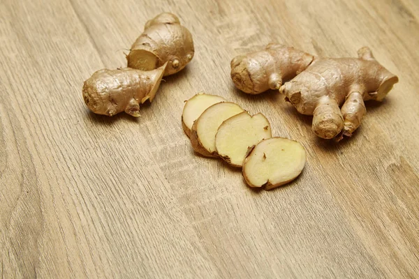 Ham zencefil kökü rustik ahşap masa arka plan üzerine dilimlenmiş