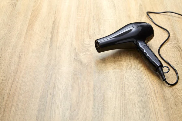 Modern hair dryer on wooden table background.