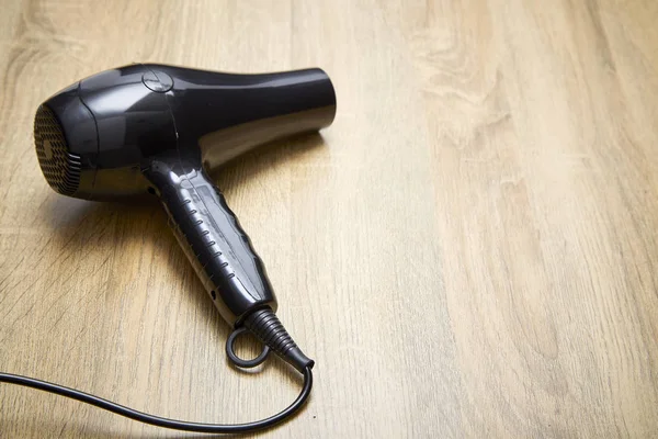 Modern hair dryer on wooden table background.