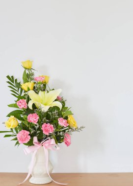 Buket sarı Lily Rose sarı çiçek ve bir vazo içinde pembe karanfil yaprakları