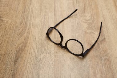Ahşap arka planda siyah çerçeveli gözlükler, masa. Yukarıdan görüntüle.