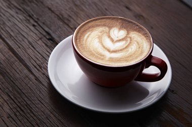 Kırmızı sıcak latte sanat üzerinde ahşap masa kahve fincan. Vintage renk tonu