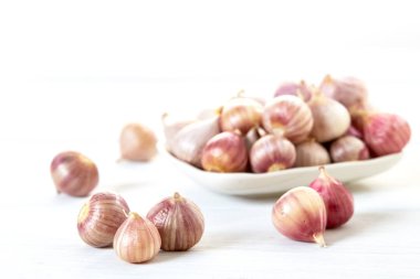 Ahşap beyaz masa arka plan üzerinde seramik kase taze sarımsak