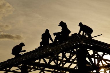 Gökyüzü ile bir çatı üst arka planda çalışma siluet yüklenici