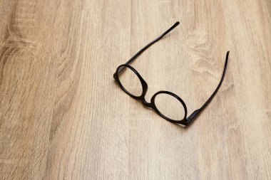 Ahşap arka planda siyah çerçeveli gözlükler, masa. Yukarıdan görüntüle.