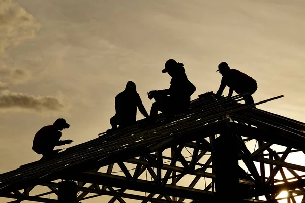 Gökyüzü ile bir çatı üst arka planda çalışma siluet yüklenici