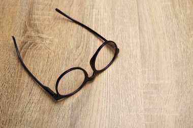 Ahşap arka planda siyah çerçeveli gözlükler, masa. Yukarıdan görüntüle.