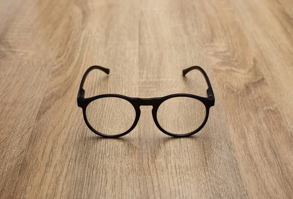Glasses in black vintage frame on wooden background, table. View from above.