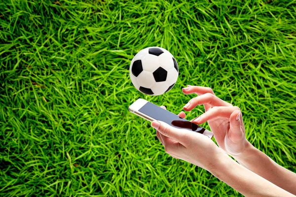 Sahada futbol topu karşı akıllı telefon tutan el close-Up