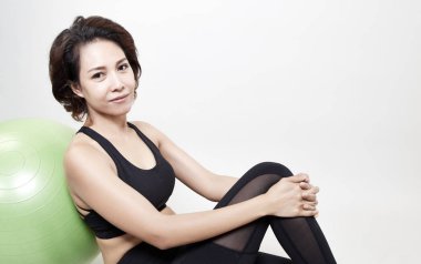 Seksi genç Asyalı kız egzersiz fitness topu gri arka plan üzerinde gülümseme. temiz spor salonunda. Spor Kulübü. Yoga aerobik sınıfında. spor eğitmeni, kilo kaybı. yağ yakma. ya da sağlıklı welness yaşam tarzı kavramı. Kopya alanı ile