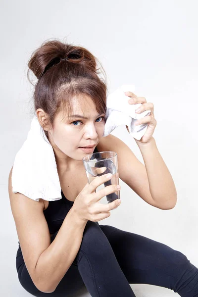 锻炼亚洲妇女饮用水在她的脖子在白色背景附近拿着白色毛巾 — 图库照片