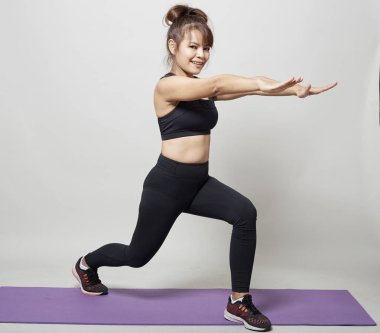 Stüdyo gri arka plan üzerinde Asyalı bir kadın tarafından germe egzersiz duruş