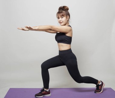 Stüdyo gri arka plan üzerinde Asyalı bir kadın tarafından germe egzersiz duruş