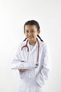 Tıbbi üniforma beyaz arka plan üzerinde izole stetoskop ile oynarken küçük boy gülümseyerek