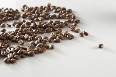 birden fazla kavrulmuş kahve çekirdekleri açık cam düz yatıyordu, beyaz zemin üzerine dökülür.