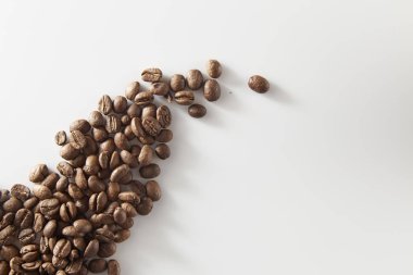 birden fazla kavrulmuş kahve çekirdekleri açık cam düz yatıyordu, beyaz zemin üzerine dökülür.
