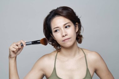 Gri arka planda güzellik salonu iç genç kadın portresi makyaj uygulamak güzellik Asyalı kız. Cilde uygulanan sesi.