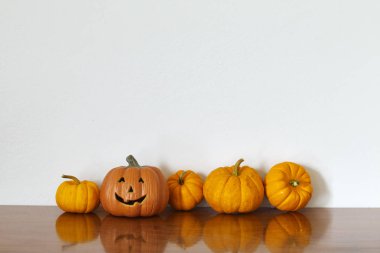 Ahşap masa beyaz duvar arka planda turuncu halloween balkabağı.