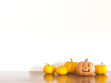 Ahşap masa beyaz duvar arka planda turuncu halloween balkabağı.