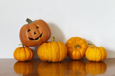 Ahşap masa beyaz duvar arka planda turuncu halloween balkabağı.