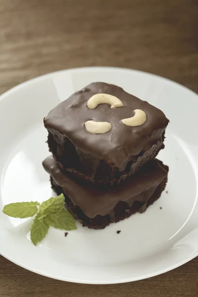 Homemade chocolate brownies topping with cashew nut and mint stacked on wood table with copy space. Brownie is one type of chocolate cake