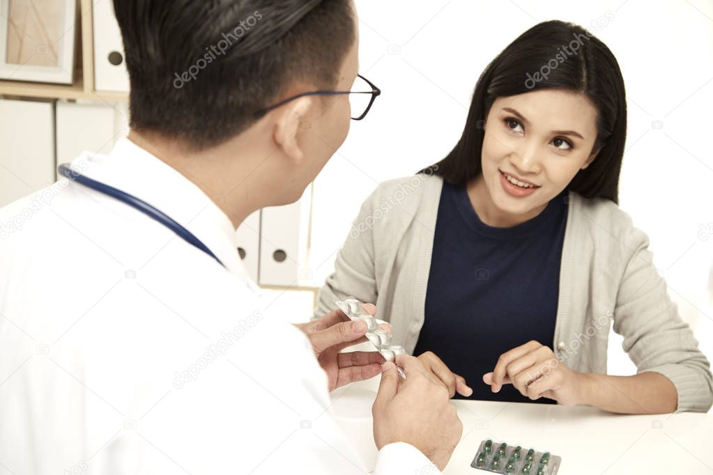 A young mother is talking to a doctor in his doctor's office. he is dressed in a white medical gown, Family planning concept