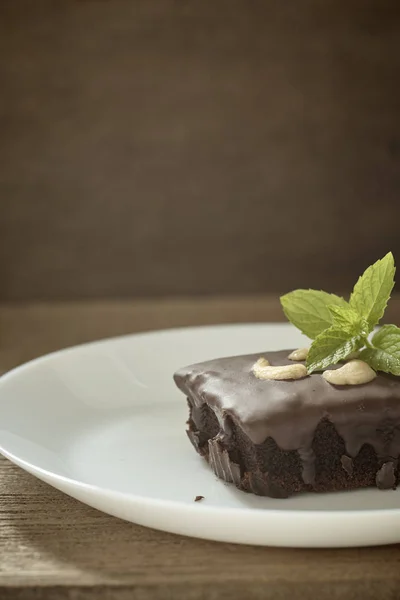 Homemade chocolate brownie topping with cashew nut and mint stacked on wood table with copy space. Brownie is one type of chocolate cake