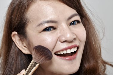 Genç güzel kadın kozmetik toz fırça yüz beyaz arka plan üzerinde uygulama.