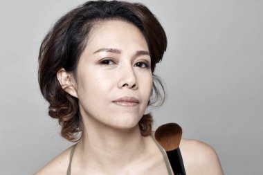 Asya genç güzel kadın kozmetik toz fırça yüz beyaz arka plan üzerinde uygulama.