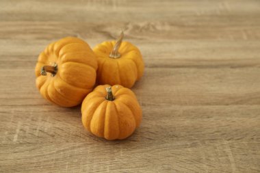 Parlak sarı ve turuncu renk ile kök tasarım ve metin için boş alan ile hafif kahverengi ahşap masa üzerinde üç olgun kabaklar