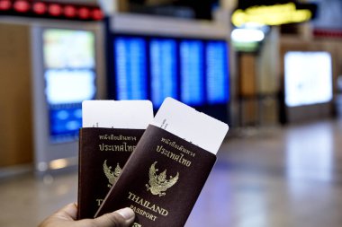 Adamın sol elinde tutan Tayland pasaportu ogto Japonya Havaalanı Uçuş programı ile bulanık, seyahat kavramı, iç mekan aydınlatma, gece