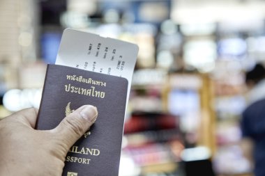 Adamın sol elinde tutan Tayland pasaportu ogto Japonya Havaalanı Uçuş programı ile bulanık, seyahat kavramı, iç mekan aydınlatma, gece