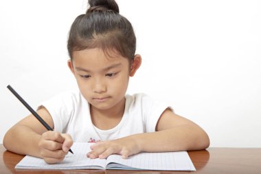 Asyalı küçük kız onun ödev, doğa yanındaki güneşli harfler için boş alan sabah yaparken konsantre