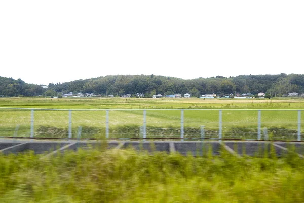 日本的稻田与农庄之间的日本列车拍摄的模糊视图 — 图库照片